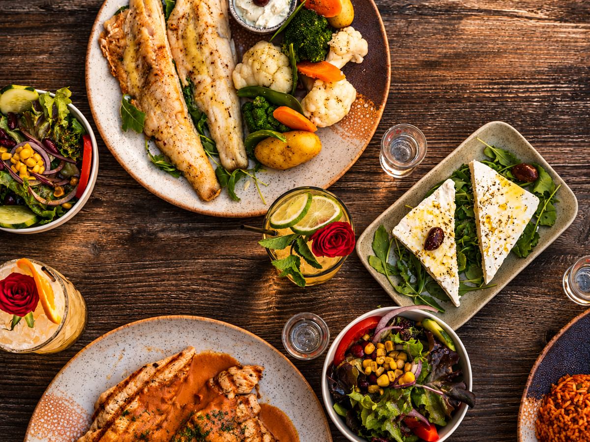 Gedeckter Tisch von oben mit Fisch, Feta, Salaten und Vorspeisen